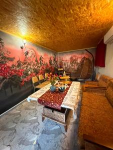 a living room with a table and a painting on the wall at Dadu's Guesthouse in Samtredia