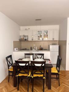 a dining room table with chairs and a kitchen at Sirius Apartment in Škaljari