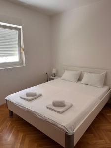 a large bed in a white room with a window at Sirius Apartment in Škaljari