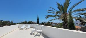 a balcony with white chairs and a palm tree at Stone Suites in Famagusta +89 photos