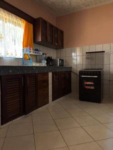 a kitchen with brown cabinets and a black stove at Barizi Cottage in Tulu