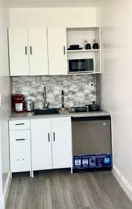 a kitchen with white cabinets and a sink and a dishwasher at Private Cozy Studio in Sunrise