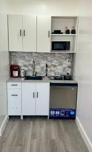 a kitchen with white cabinets and a sink and a microwave at Private Cozy Studio in Sunrise