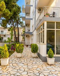 a stone walkway in front of a building with potted plants at Hotel Gonaj in Velipojë +7 photos