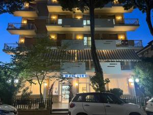 a white car parked in front of a building at night at Hotel Primula in Lido di Savio
