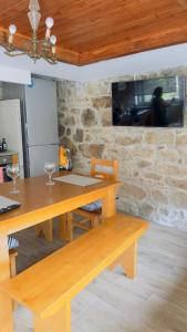 a wooden table and bench in a room with a tv at Casa dos Devezas in São Gregório