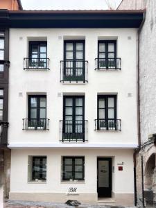 a white building with black windows and a door at BM Apartamentos in Ribadesella