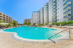 a large swimming pool with chairs and buildings at Blue Gold Escape - Ocean view, airco, heated pool in Adeje