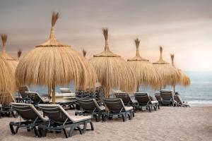 a group of chairs and straw umbrellas on a beach at Blue Gold Escape - Ocean view, airco, heated pool in Adeje