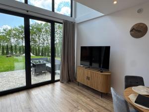 a living room with a flat screen tv and a table at Stodoła Parysa in Wola Korytnicka +12 photos