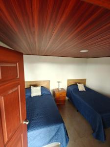 a bedroom with two beds and a wooden wall at Altura & lago in San Nicolás