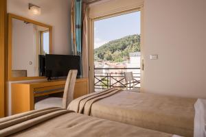 a bedroom with a bed and a desk with a television at Plaza Hotel in Zakynthos