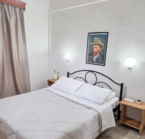 a bedroom with a bed and a painting of a man at Chrysanthi Melitsa apts. in Sidari