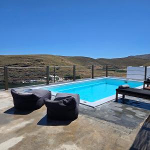a swimming pool with two couches and a bench at Utopia Kythnos Althea in Kithnos