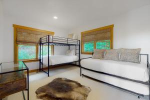 a bedroom with two beds and a table and windows at Tuckerman Tollhouse in Jackson