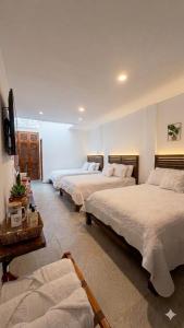 a hotel room with three beds and a tv at La Toscana Hostel in Villa de Leyva +16 photos