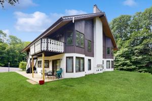 a house with a balcony on a green lawn at White Mountain Getaway in Bartlett