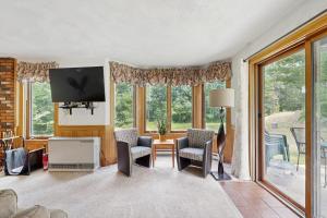 a living room with chairs and a tv and windows at White Mountain Getaway in Bartlett