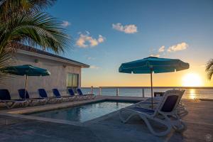 a pool with chairs and umbrellas and the ocean at The Sands Hotel in Cockburn Town