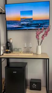 a table with a tv on a wall with glasses and flowers at TreA Suites By Aria in Vlorë