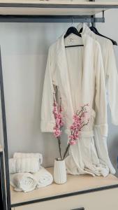 a white robe and towels on a shelf with a vase with flowers at TreA Suites By Aria in Vlorë +62 photos