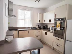 a kitchen with white cabinets and a table in it at Sand Castle in Weymouth