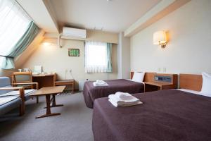 una camera d'albergo con 2 letti e una scrivania di Select Inn Yaizu Ekimae a Yaizu
