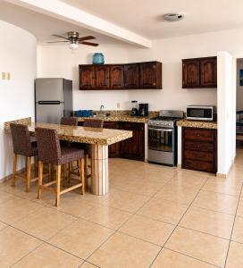 a kitchen with wooden cabinets and a table with chairs at Mar Real Suites Guayabitos in Rincon de Guayabitos