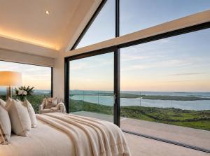 a bedroom with a large bed and a large window at Luxury Glass Villa with Hot Tub & Sea Views - Connemara in Roundstone