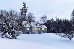 a blue house in the snow with trees at Campton White Mountains Retreat in Campton