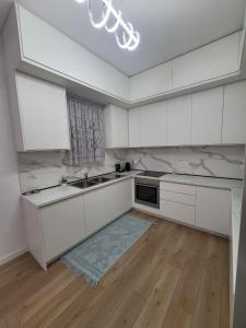 a kitchen with white cabinets and a wooden floor at Vila Mollanji in Tirana