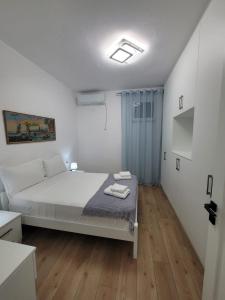 a white bedroom with a bed and wooden floors at Vila Mollanji in Tirana