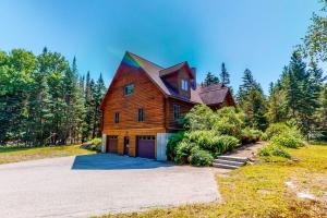 a large wooden house with a gambrel roof at White Mountain Log Home in Carroll