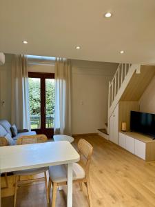 a living room with a table and a couch and a tv at Maison avec jardin à 5 min à pied de la plage, clim et parking in Royan