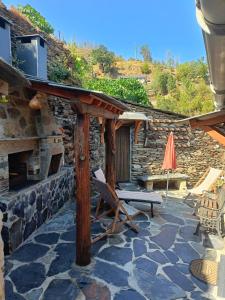 a stone house with a bench and an umbrella at Casa dos avós 23 in Castro Daire