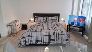 a bedroom with a black and white bed and a tv at Modern Studio Apartment with En-Suite in Peterborough