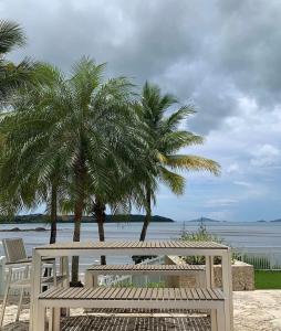 a wooden bench sitting on the beach with palm trees at The Sailor beach House Just 35 Minutes from Panama City! in Vacamonte