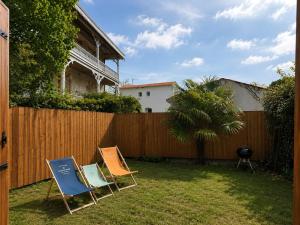 two chairs sitting in a yard next to a fence at Maison avec jardin à 5 min à pied de la plage, clim et parking in Royan
