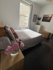 a bedroom with a bed and flowers on a table at Spacious Flat in West Kensington in London