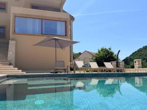 a house with a swimming pool with an umbrella at Azure Boka in Trojica