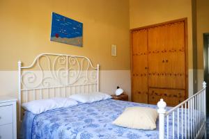 a bedroom with a white bed and a wooden door at Villa Troianiello in Carano