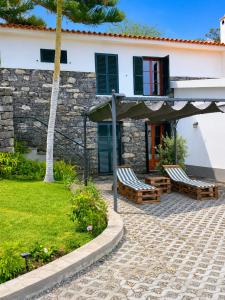 a house with two benches in front of it at Dr. Cabral Barreto in Ponta do Sol