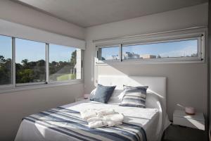 a white bedroom with a bed with towels on it at Nova pampa apart&spa in Mar de las Pampas +61 photos