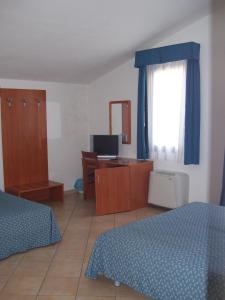 una camera con 2 letti, una scrivania e una finestra di Resort Isola Rossa a Bosa