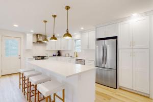 a white kitchen with a large white counter and stools at Beau in Gloucester