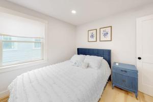 a white bedroom with a blue bed and a window at Beau in Gloucester