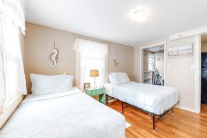 two beds in a room with white sheets at Cool Change in Hampton