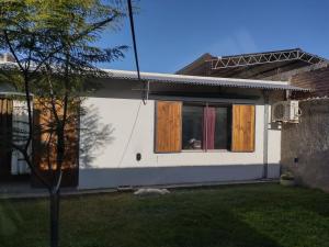 a small white house with a window and a tree at Casa XENA in Río Cuarto