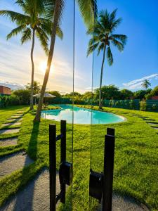 a swing in front of a pool with palm trees at Luce del sole bangalô in Fortim