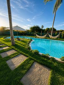 a swimming pool with palm trees and a hammock at Luce del sole bangalô in Fortim